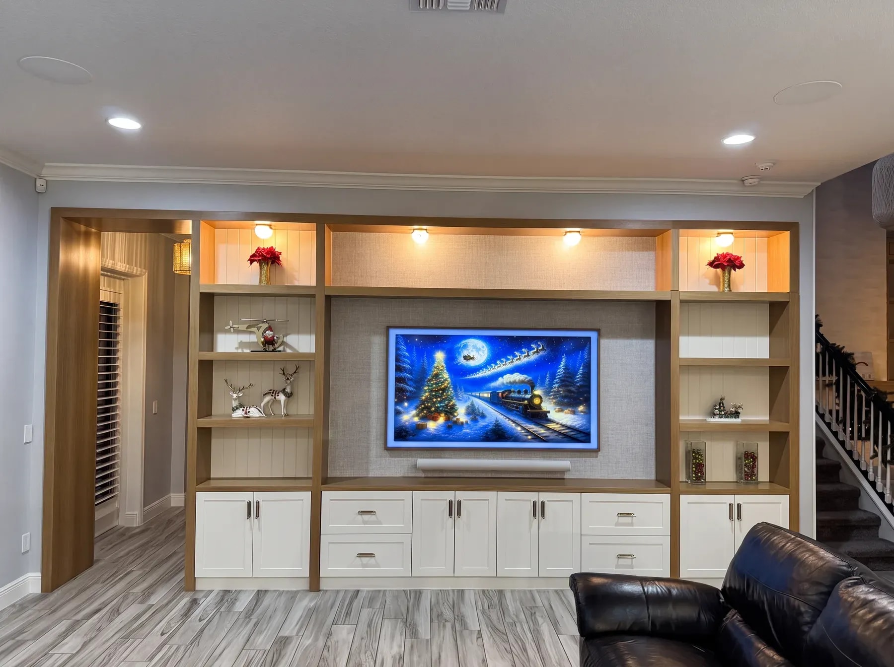 Full-wall white oak and painted entertainment built-in with a fabric-panel television surround and lit display shelves