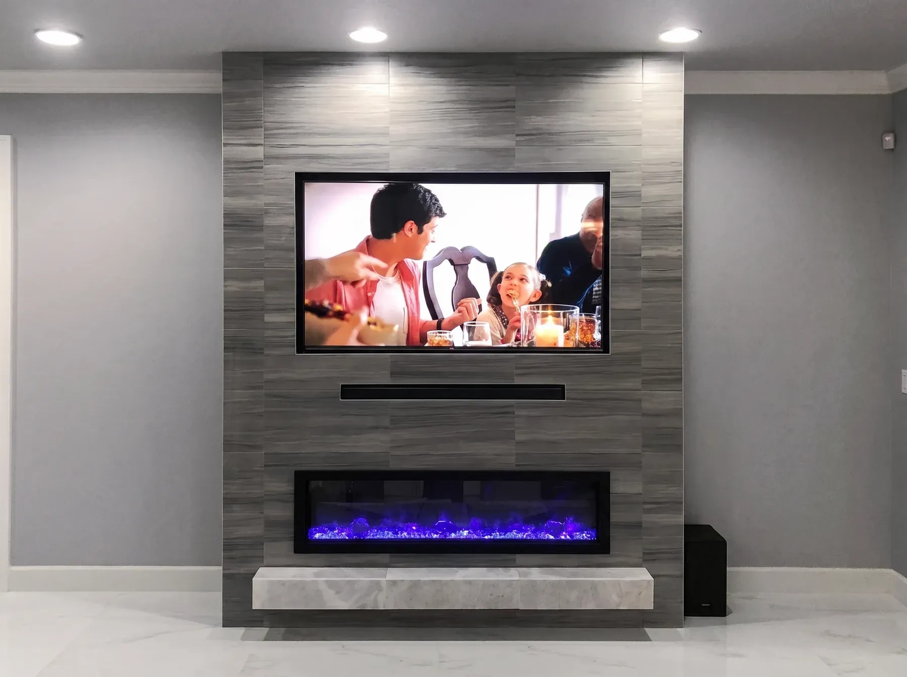 Grey vertical-grain porcelain tile wall with a floating stone hearth, linear fireplace and flush television