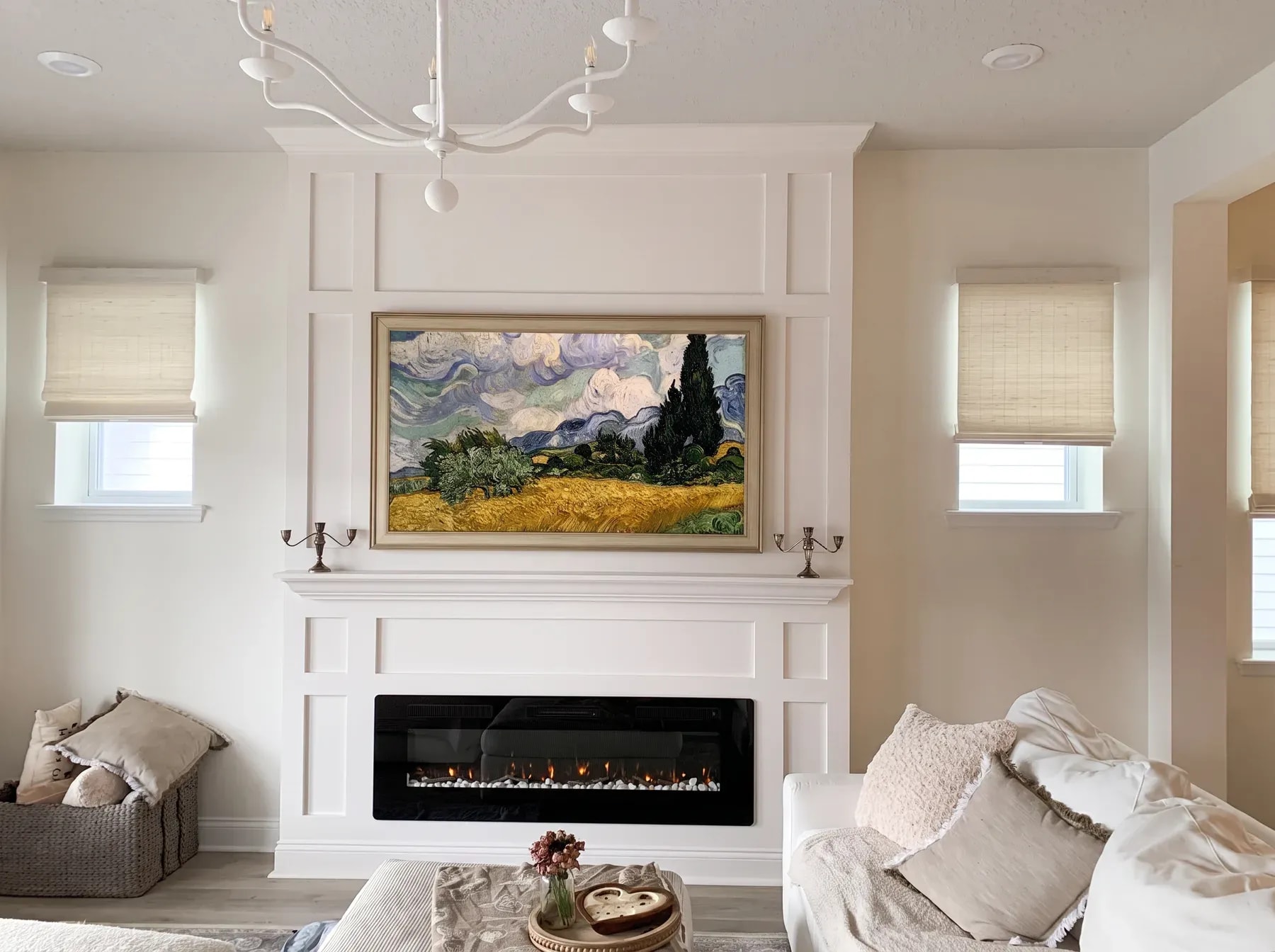 White painted millwork fireplace wall with a mantel shelf, framed-art television and linear fireplace